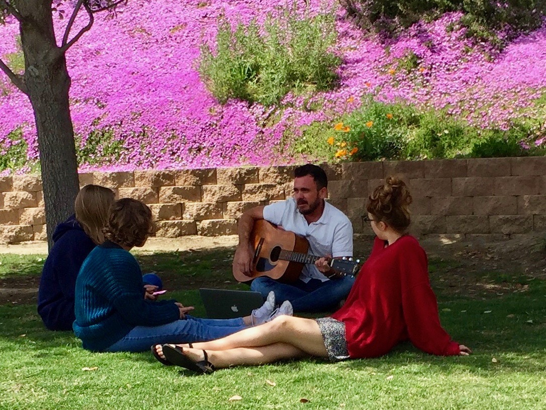 students listening to a teacher playing the guitar