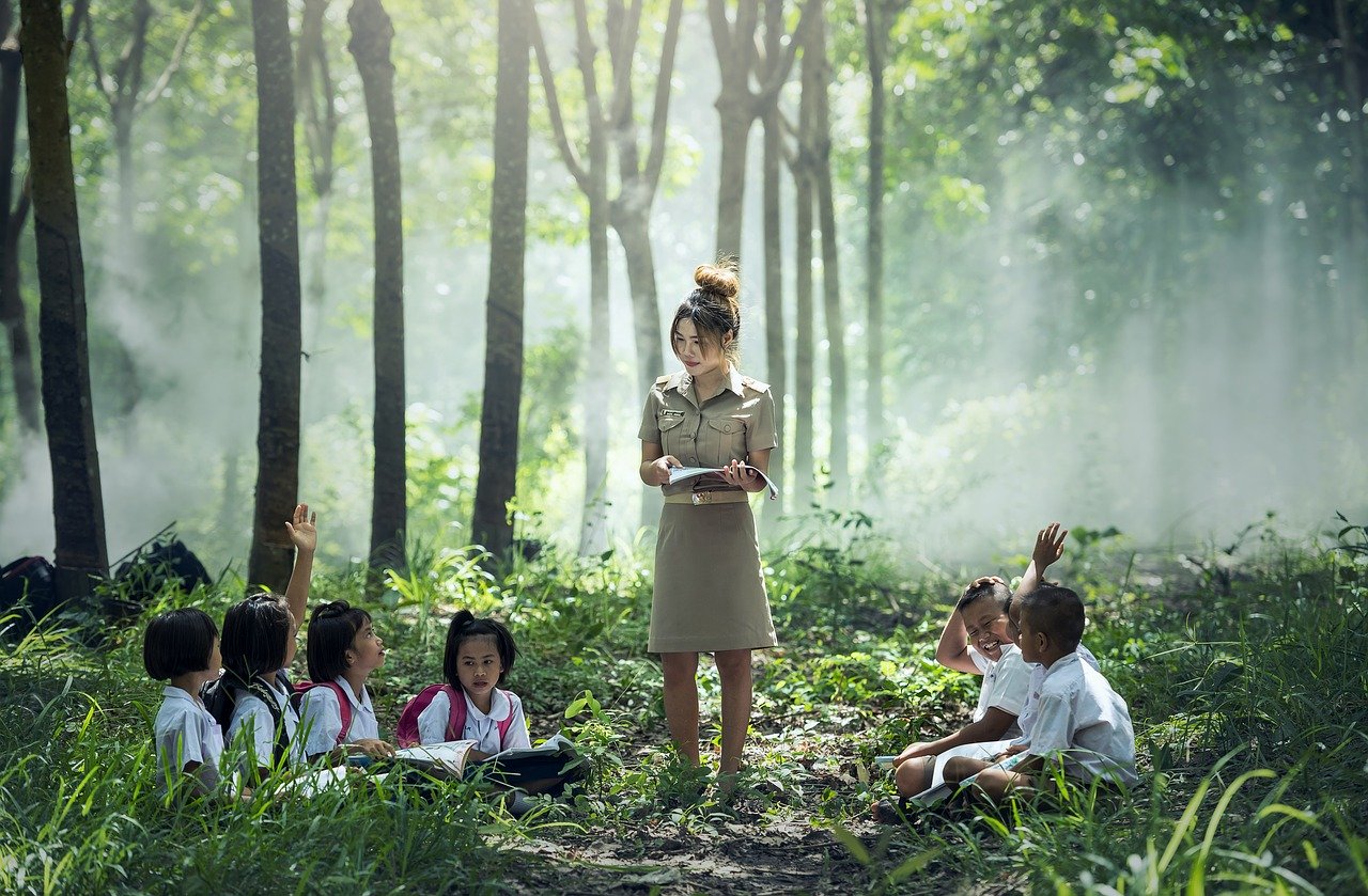 a teacher and her students having class in the woods