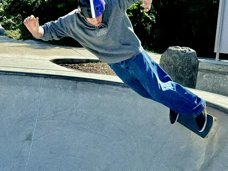 High school boy doing a skateboard trick at a skate park