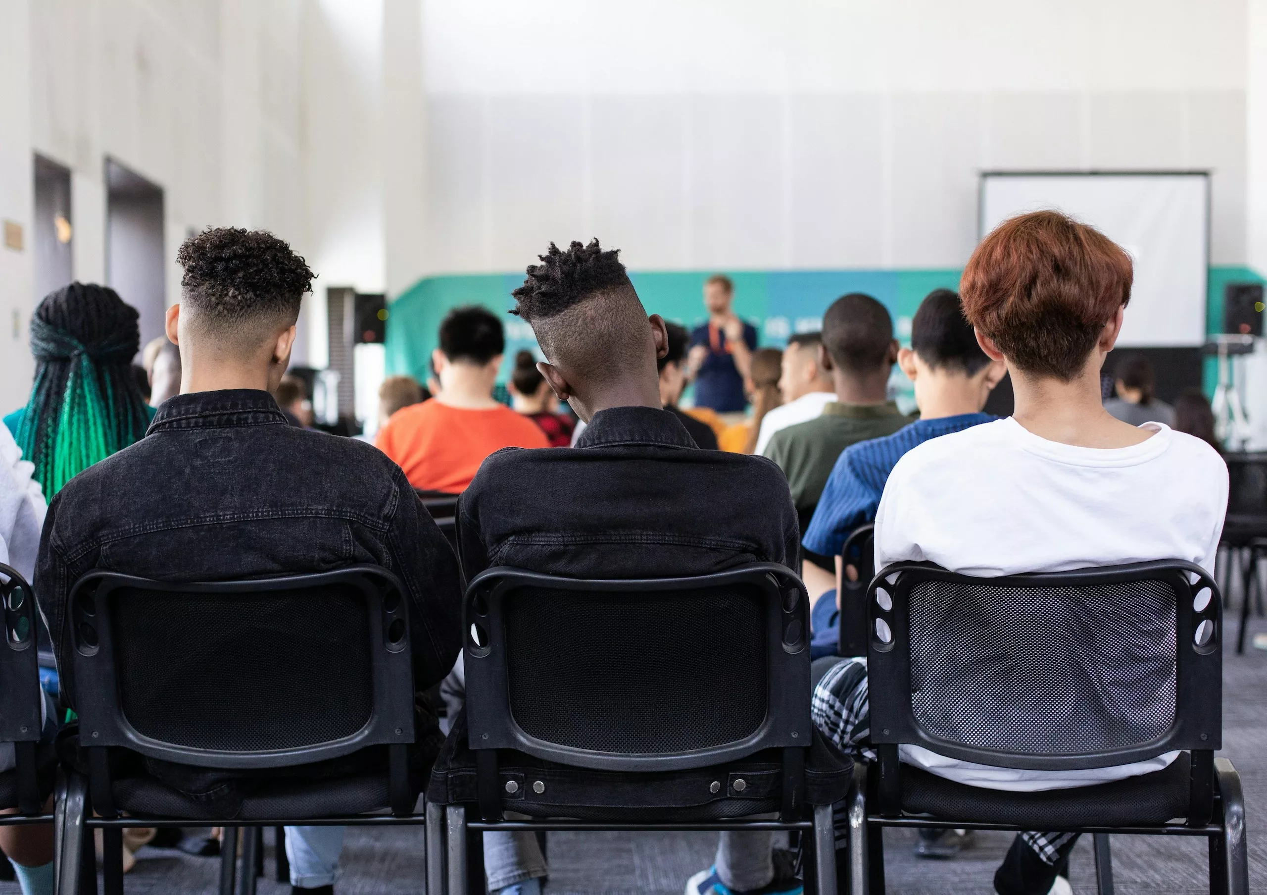 The backs of students sitting in chairs in a modern classroom