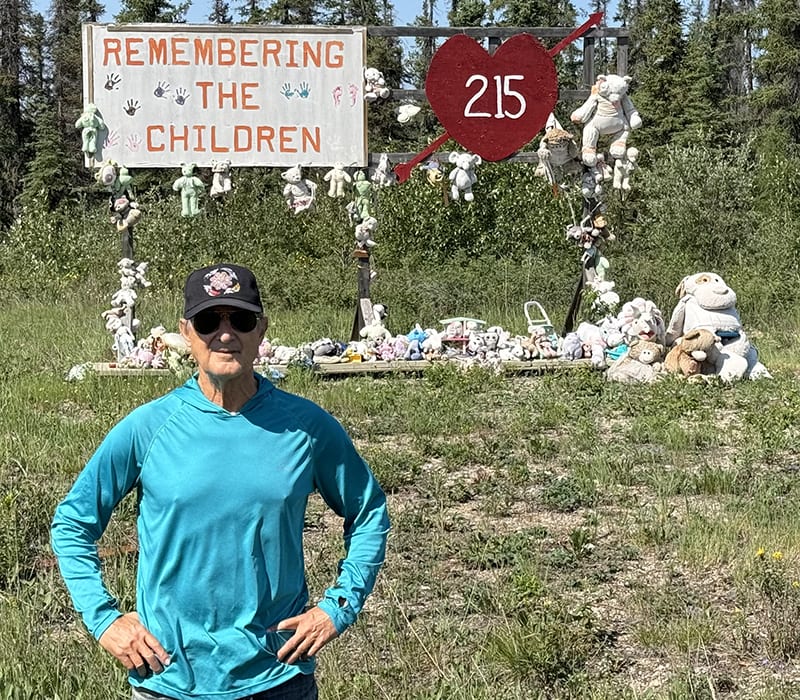 Stuart Grauer at a memorial for the Indigenous children with a sign that says "remembering the children" behind him