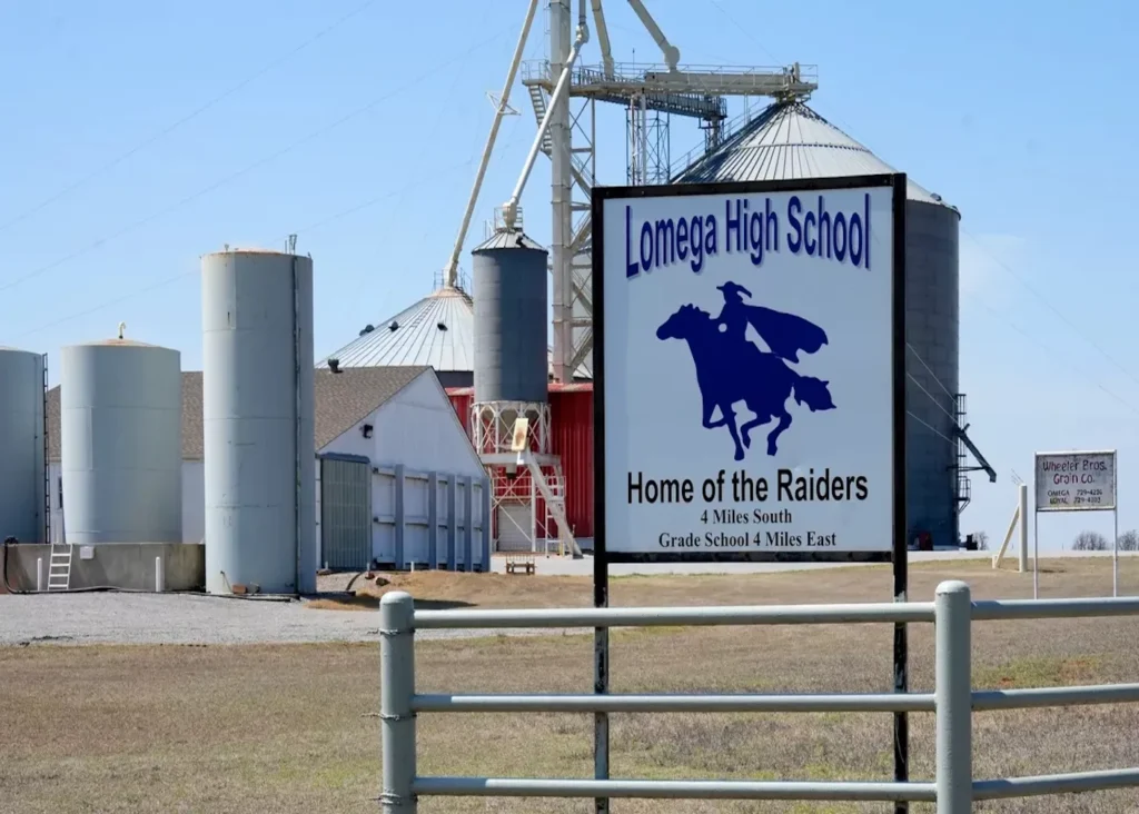 Photo of a sign that says Save Our School displayed on a fence with trees in the background