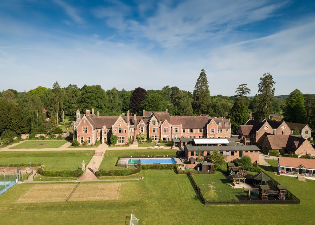 A paper sign with painted handprints with text that reads "2 schools 1 family"
